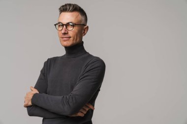 Yakışıklı, kendine güvenen, zeki görünümlü bir adam. Gri arka planda yalnız poz veriyor.