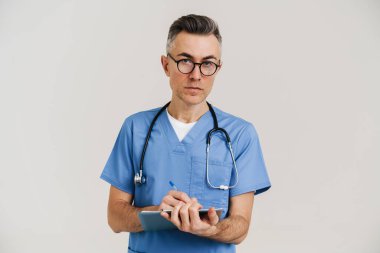 Odaklanmış gri doktor steteskop ile beyaz duvarda izole edilmiş tıbbi dosya üzerinde yazıyor.