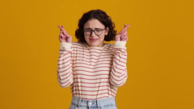 Gözlüklü güzel bir genç kız stüdyoda sarı arka planda tek başına beklerken bir dilek diliyor.