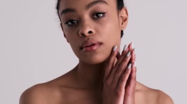 Çekici, yarı çıplak bir kadın kameraya poz veriyor. Stüdyonun gri arka planında tek başına duruyor.