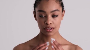 Mutlu, genç, yarı çıplak bir kadın stüdyodaki gri arka planda tek başına kameraya bakıyor.