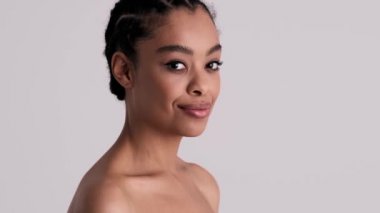 Pozitif, genç, yarı çıplak bir kadın stüdyonun gri arka planında bir şeyler fısıldıyor.