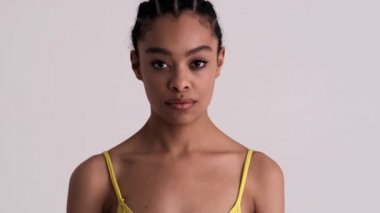 Şaşırmış bir kadın kameraya bakıyor. Stüdyoda gri bir arkaplan üzerinde tek başına duruyor.