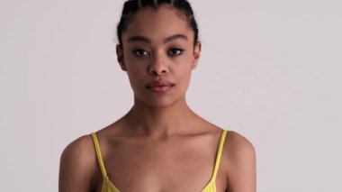 Mutlu bir kadın, stüdyodaki gri bir arka planda tek başına ayakta durarak kazanan hareketi yapıyor.