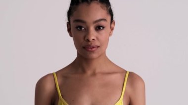 Mutlu bir Amerikalı kadın iyi bir jest yapıyor. Stüdyonun gri arka planında tek başına duruyor.