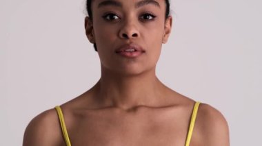 Güzel bir Amerikalı kadın stüdyodaki gri bir arka planda tek başına poz veriyor.