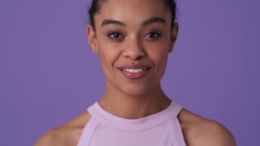 Sıradan kıyafetler giyen başarılı genç bir kadın, stüdyodaki menekşe arkaplanından izole bir şekilde duruyor.