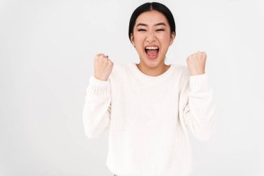 Asyalı heyecanlı güzel kız çığlık atıyor ve kazanan hareketi yapıyor beyaz arka planda izole edilmiş.