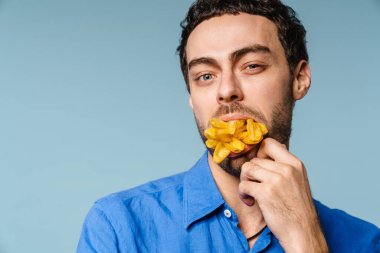 Kendine güveni tam yakışıklı adam, mavi arka planda patates kızartması ile poz veriyor.