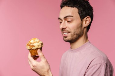 Pembe arka planda poz verirken gülümseyen yakışıklı adam.