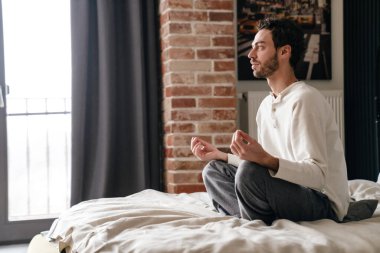 Huzurlu Kafkasyalı adam uyuduktan sonra yatakta meditasyon yapıyor.
