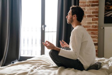 Huzurlu Kafkasyalı adam uyuduktan sonra yatakta meditasyon yapıyor.