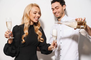 Beauitufl genç, şık giyimli Sevgililer Günü 'nü kutlayan beyaz arka planda izole edilmiş şampanya içen adam içki dolduruyor.