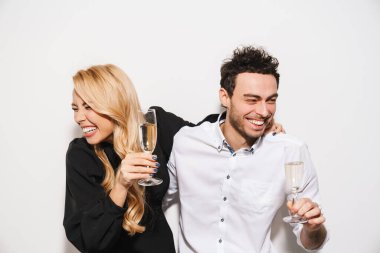 Beauitufl genç mutlu, şık giyimli sevgililer gününü kutlayan beyaz arka planda izole edilmiş şampanya içen, gülen bir çift.