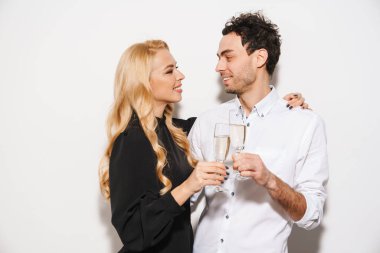 Beauitufl genç mutlu, şık giyimli sevgililer gününü kutlayan beyaz arka planda izole edilmiş şampanya içen çift.