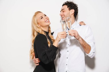 Beauitufl genç mutlu, şık giyimli sevgililer gününü kutlayan beyaz arka planda izole edilmiş şampanya içen çift.