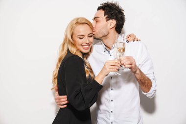 Beauitufl genç mutlu, şık giyimli sevgililer gününü kutlayan, beyaz arka planda izole edilmiş şampanya içen, öpüşen bir çift.