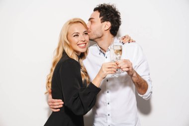 Beauitufl genç mutlu, şık giyimli sevgililer gününü kutlayan, beyaz arka planda izole edilmiş şampanya içen, öpüşen bir çift.