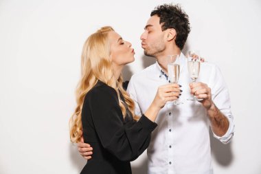 Beauitufl genç mutlu, şık giyimli sevgililer gününü kutlayan, beyaz arka planda izole edilmiş şampanya içen, öpüşen bir çift.