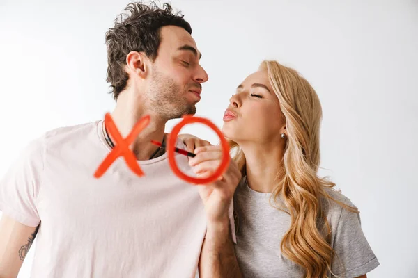 Lovely beautiful young couple drawing xo symbol isolated over white background, celebrating Valentines day