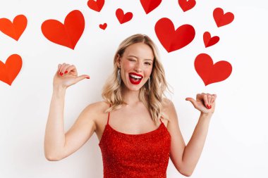 Neşeli güzel kız gülüyor ve kendini işaret ediyor. Beyaz arka planda, kalplerle izole edilmiş.