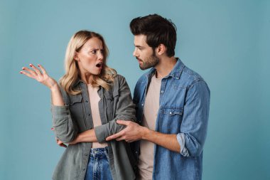 Yakışıklı esmer adam mavi arka planda izole edilmiş bir kızla sarılıp konuşuyor.