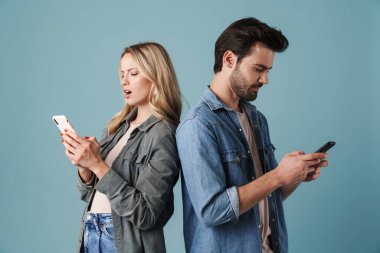 Beyaz erkek ve kadın akıllı telefon kullanırken arka arkaya mavi arka planda izole bir şekilde duruyorlar.