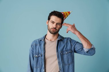 Parti konisindeki yakışıklı üzgün adam mavi arka planda izole edilmiş atış hareketi gösteriyor.