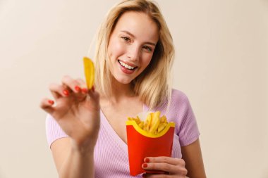 Beyaz arka planda izole edilmiş kameraya patates kızartması gösterirken gülümseyen güzel kız.