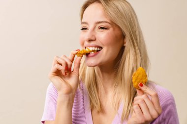 Beyaz arka planda izole edilmiş kamerada nugget yerken gülümseyen güzel kız.