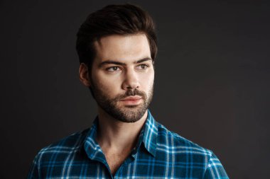 Esmer, yakışıklı, tıraşsız, poz veren, siyah arka planda yalnız gezen adam.