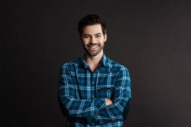 Neşeli, yakışıklı, esmer, gülümseyen ve siyah arka planda izole edilmiş kameraya bakan adam.