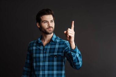 Tıraşsız, mutlu, yakışıklı, siyah arka planda, parmağını yukarı kaldıran adam.