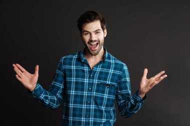 Heyecanlı yakışıklı adam elleri havada poz veriyor siyah arka planda izole edilmiş.