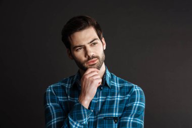 Tıraşsız yakışıklı adamın siyah arka planda yalnız poz verip bir kenara baktığını düşünmek.