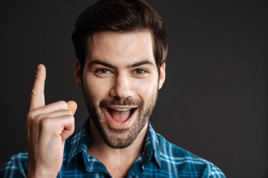 Heyecanlı yakışıklı adam, siyah arka planda dışlanmış bir şekilde işaret ediyor.