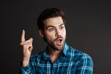 Şok olmuş yakışıklı adam, siyah arka planda dışlanmış bir şekilde işaret ediyor.