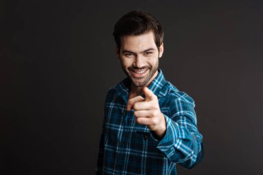 Siyah arka planda izole edilmiş kamerayı gösteren neşeli, yakışıklı esmer adam.