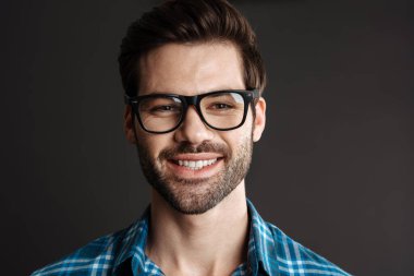 Siyah arka planda izole edilmiş kamerada poz veren gözlüklü, gülümseyen acımasız adam.