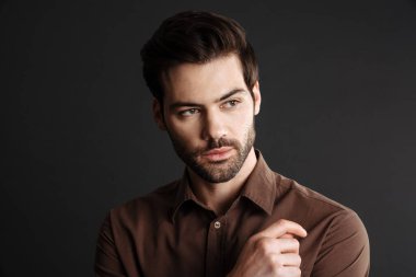 Esmer, yakışıklı, tıraşsız, poz veren, siyah arka planda yalnız gezen adam.