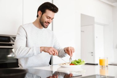 Mutfakta kahvaltı ederken gülümseyen yakışıklı adam.