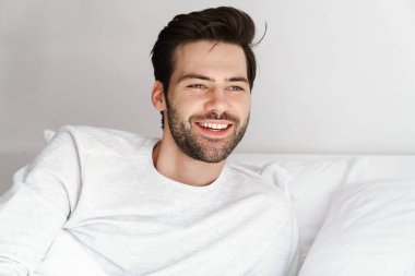 Evde dinlenirken gülümseyen yakışıklı genç adam.