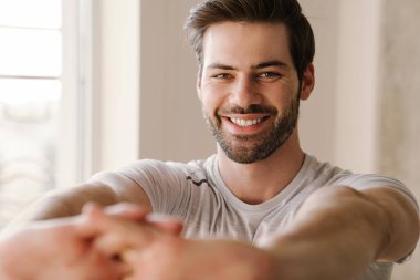 Neşeli atletik adam evde çalışırken kollarını açıyor.