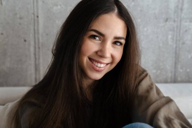 Evdeki kanepede dinlenirken gülümseyen güzel esmer kız.