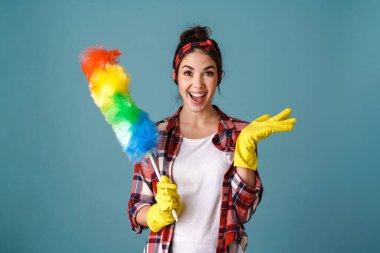 Telif alanı ve renkli toz bezi tutan eldivenli heyecanlı kadın mavi arka planda izole edilmiş.