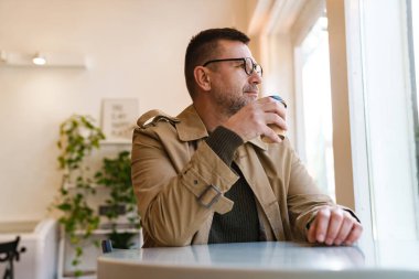 Yakışıklı, kendine güvenen iş adamı, modern kahve dükkanında kahvaltı yapıyor.