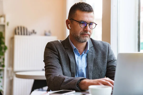 Bonito Empresário Confiante Trabalhando Computador Portátil Enquanto Sentado Café Dentro — Fotografia de Stock