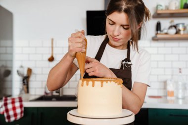 Mutfakta kremalı kek yapan fırıncı kadının kamera görüntüleri.