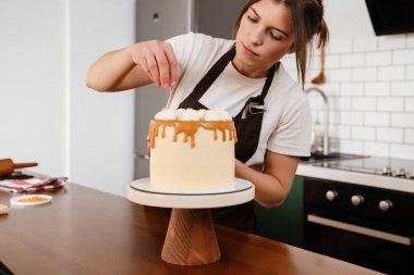 Güzel odaklı fırıncı kadın evde kremalı kek yapıyor.