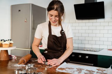 Güzel, mutlu fırıncı kadın evde Noel kurabiyesi yapıyor.